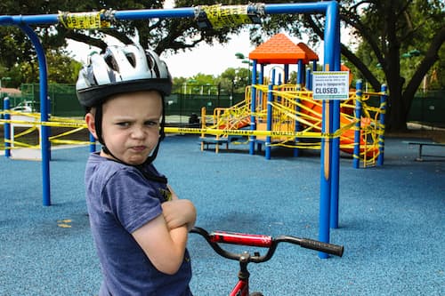 Child with crossed arms and frowning face in a play park
