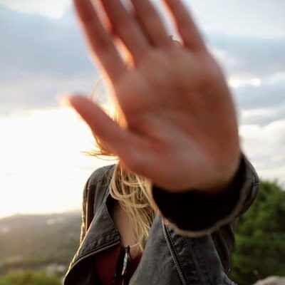 Young person putting their hand up to the camera to hide their face